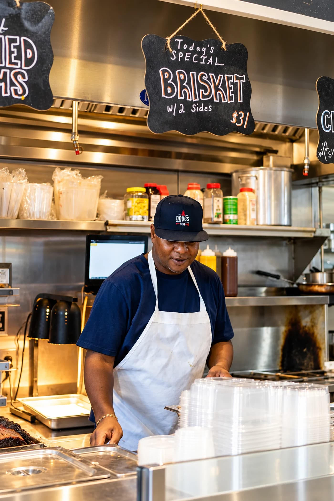 The Doug's North Carolina BBQ cook at work under the brisket special sign
